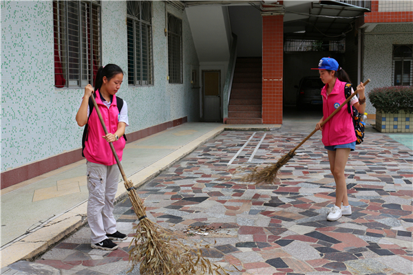 志愿者为福利院的孩子们打扫活动的大院