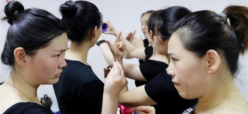 5月26日，两名舞蹈队员在观看手机上的教学视频时互相交流。 在上海闵行区古美路街道，有一个由听力障碍者组成的舞蹈团队——古美彩韵聋人舞蹈艺术队。舞蹈队现有20名队员，年龄从20岁到40岁，由上海戏剧学院舞蹈学院的老师每周一次为队员们提供训练指导。对舞蹈艺术的热爱，让这些听力障碍者走到了一起，在无声世界里舞出精彩人生。