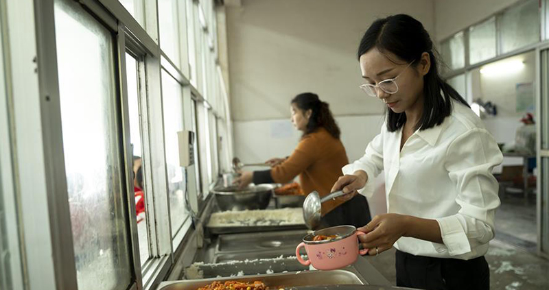 方荣在罗田县希望小学食堂给学生打饭。