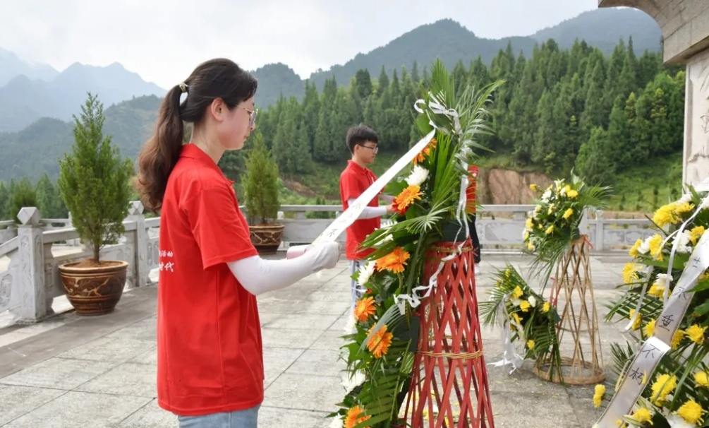 图为实践团队长与临时团支部书记整理花篮上的挽联