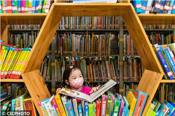 ↑2022年3月16日，在安徽省合肥市少年儿童图书馆“童悦绘本馆”，一名小朋友在书架上阅读绘本。（来源：新华网 CICPHOTO/袁兵 摄）