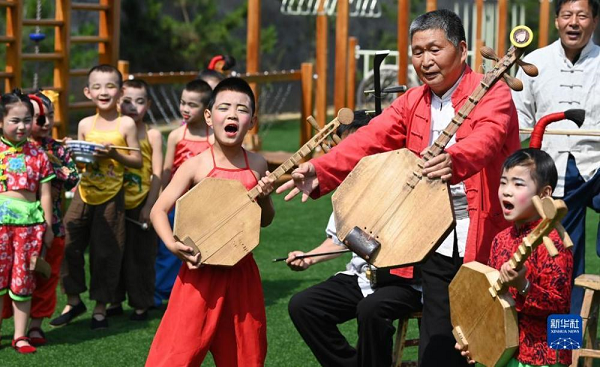 　   5月26日，黄河老腔艺术团的老艺人在幼儿园为孩子们传授老腔艺术技巧。新华社记者 陶明 摄